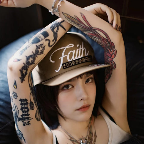 Person wearing a cap with 'Faith' text, surrounded by tattoos on arms and legs.